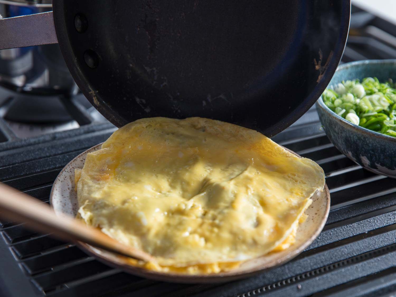 Sliding a layer of omelette out of the skillet into the serving plate.