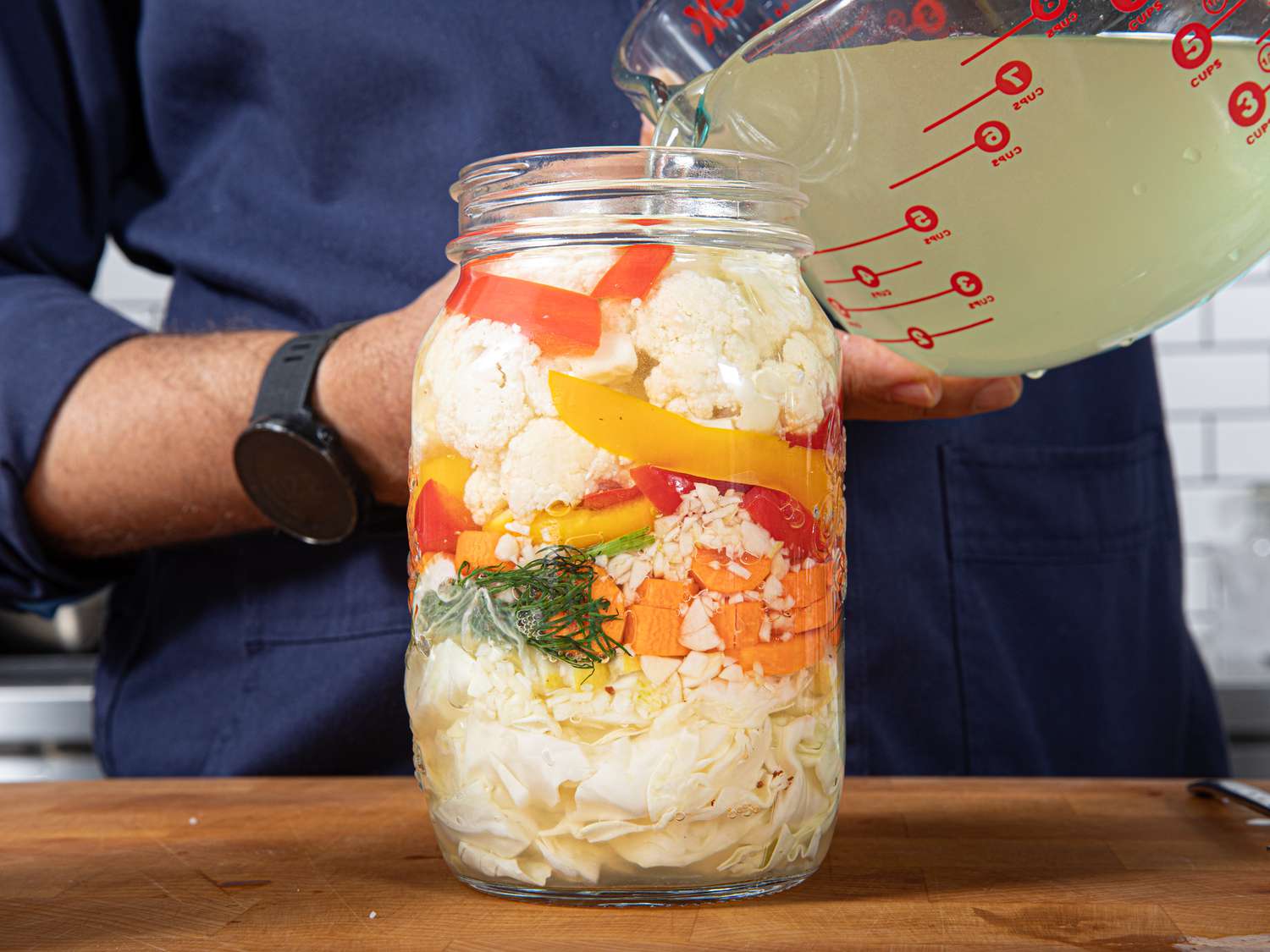 Side view of vegetables in a jar with pickling liquid being added to it