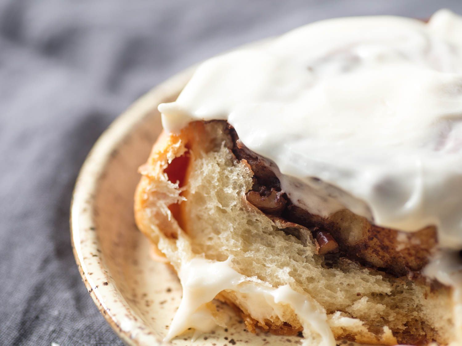 Close-up of the interior of a cinnamon roll frosted with cream cheese icing.