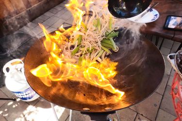 食物被扔在炒锅与火焰在户外炒锅燃烧器gydF4y2Ba