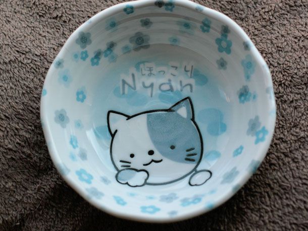 蓝色和白色的猫食碗与小猫插图在底部。