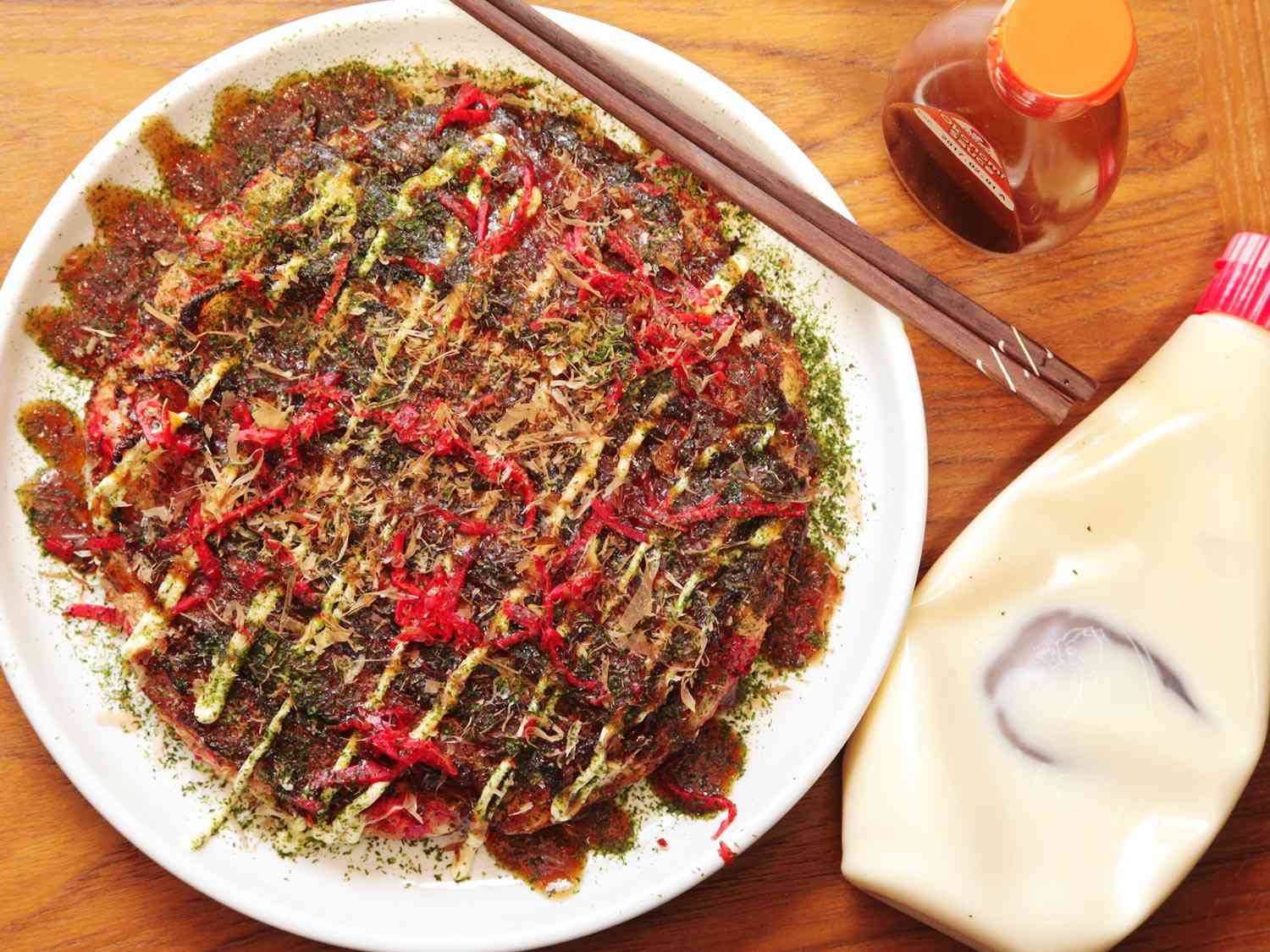 An okonomiyaki, a savory Japanese pancake, on a white plate