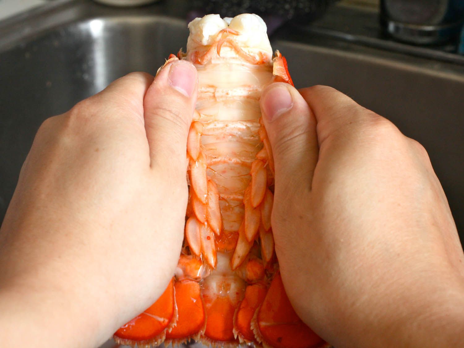 将煮熟的龙虾尾从壳上取下。