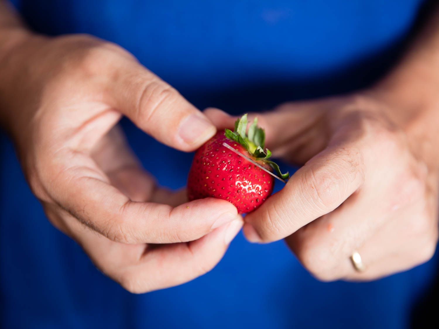 A pairing knife hulling a strawberry