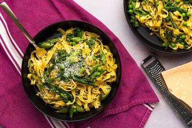 Pasta Primavera served inside a dish, drizzled with olive oil, sprinkled with freshly ground black pepper, and served with grated Parmigiano-Reggiano