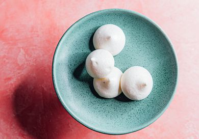 aquafaba-cardamom meringue cookies on a blue plate on a pink background