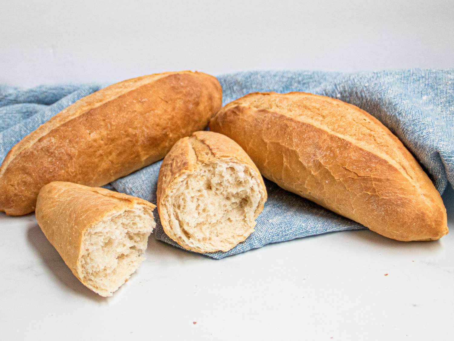 Side view of a banh mi loaf split in half with two other loafs