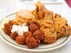 A plate of hushpuppies and chicken and a biscuit