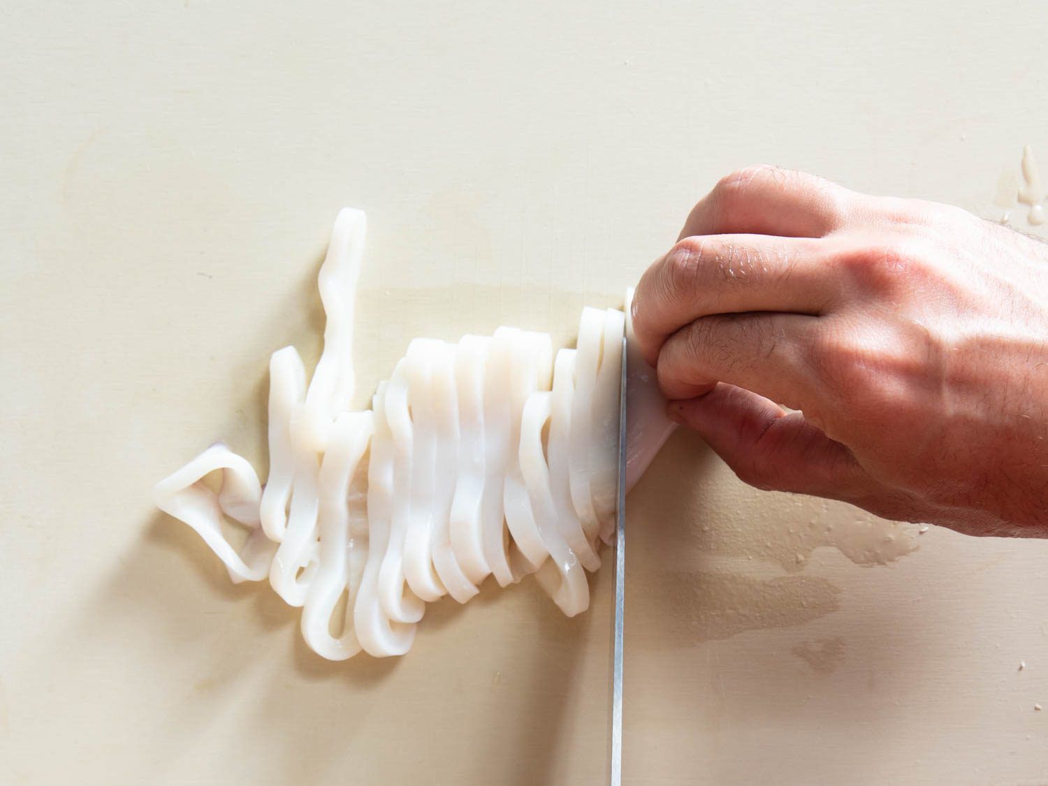 Slicing squid on a plastic cutting board