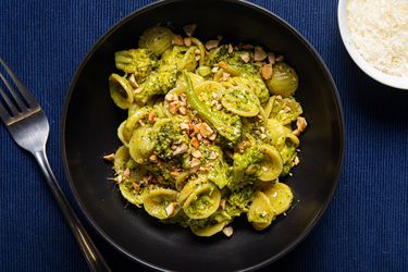 Orecchiette with broccoli and toasted hazelnuts in a black bowl.