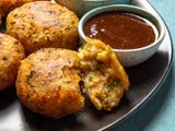 Aloo tikki on a plate with a dipper of tamarind chutney alongside