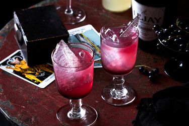 Two glasses of Crème de Cassis on a dark wood table