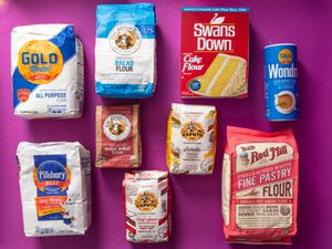 Bags of different types of flour against a purple background.