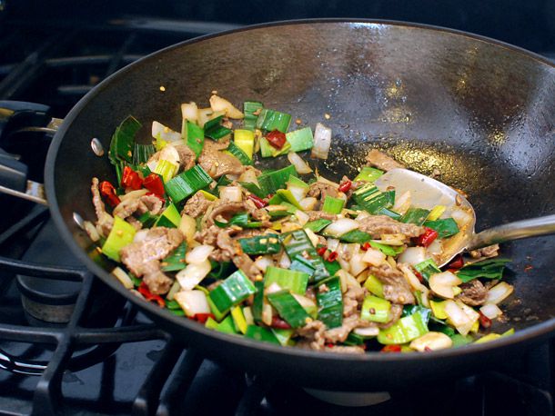 把牛肉放回锅里加入辣椒，大蒜和韭菜。
