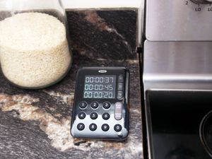 oxo triple stove timer with three times displayed on a countertop next to the stovetop