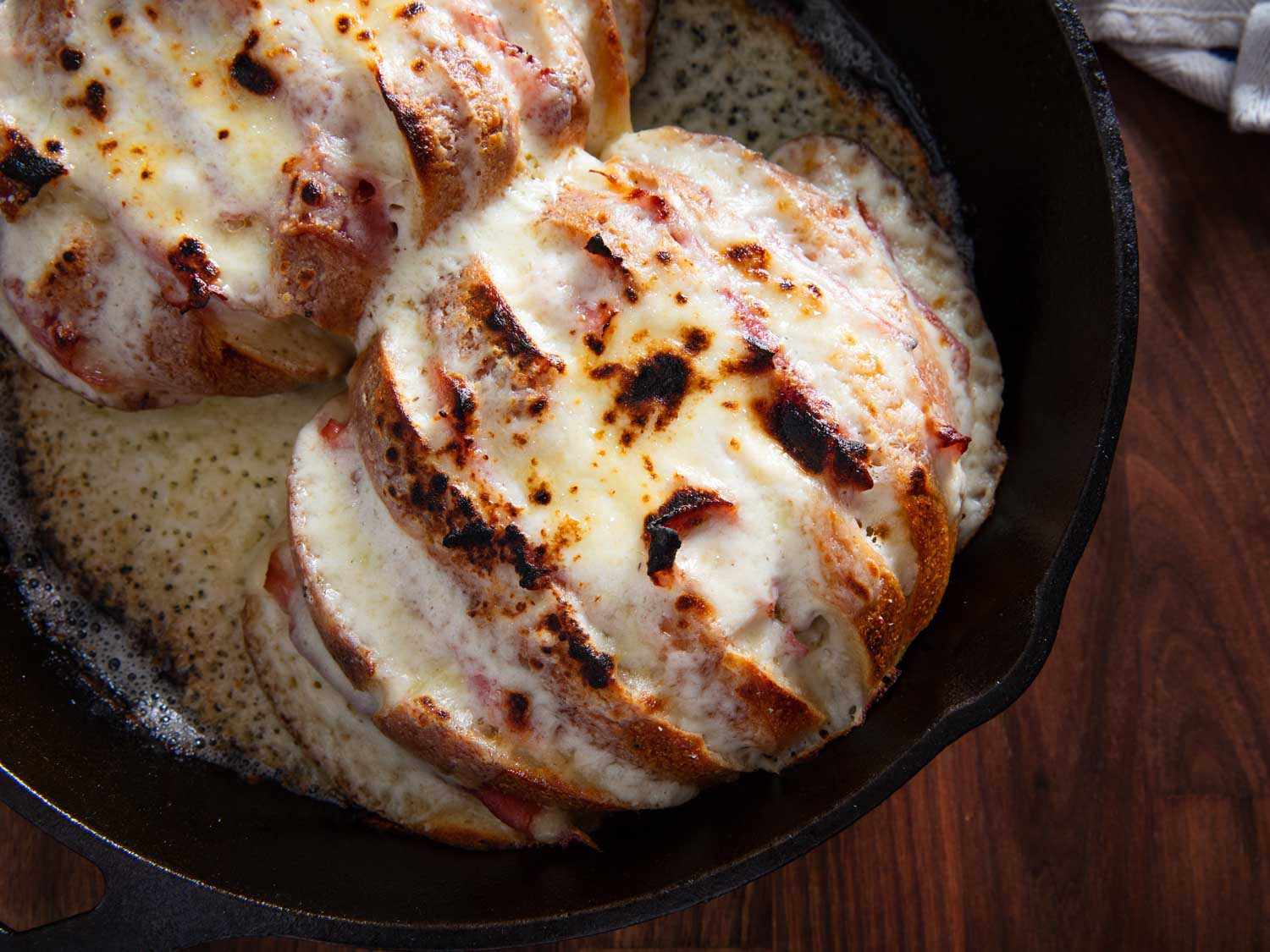 烤百吉饼(croque monsieur bagels)，像手风琴一样被垂直切开，每条缝里塞着火腿和奶酪，然后浇上奶酪莫奈酱(Mornay)，烤到局部起水泡