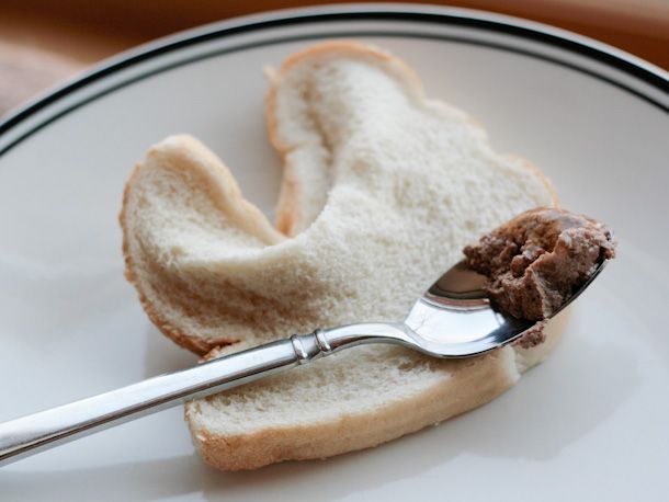 一勺湿猫粮放在一片白面包上。