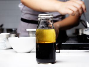 Bottle of all purpose vingeriatte on a counter with a chef cooking in the background