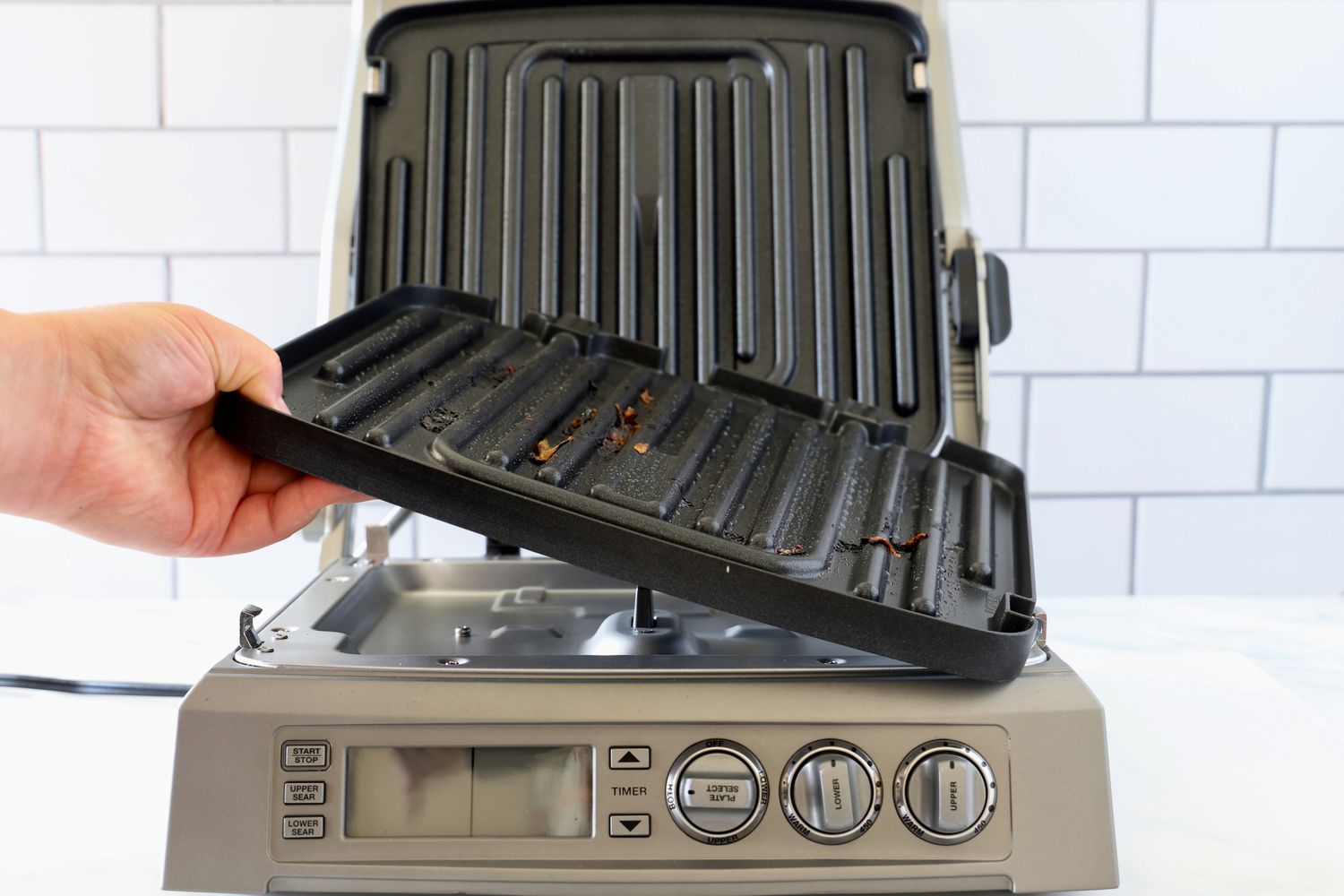 a person removing the bottom plate of a panini press