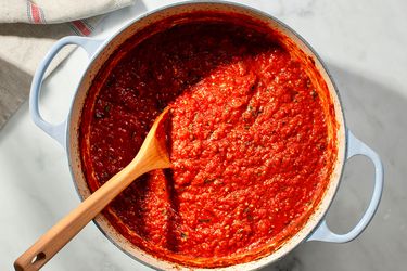 荷兰烤箱里的一锅意大利美式番茄酱，配上木勺。gydF4y2Ba