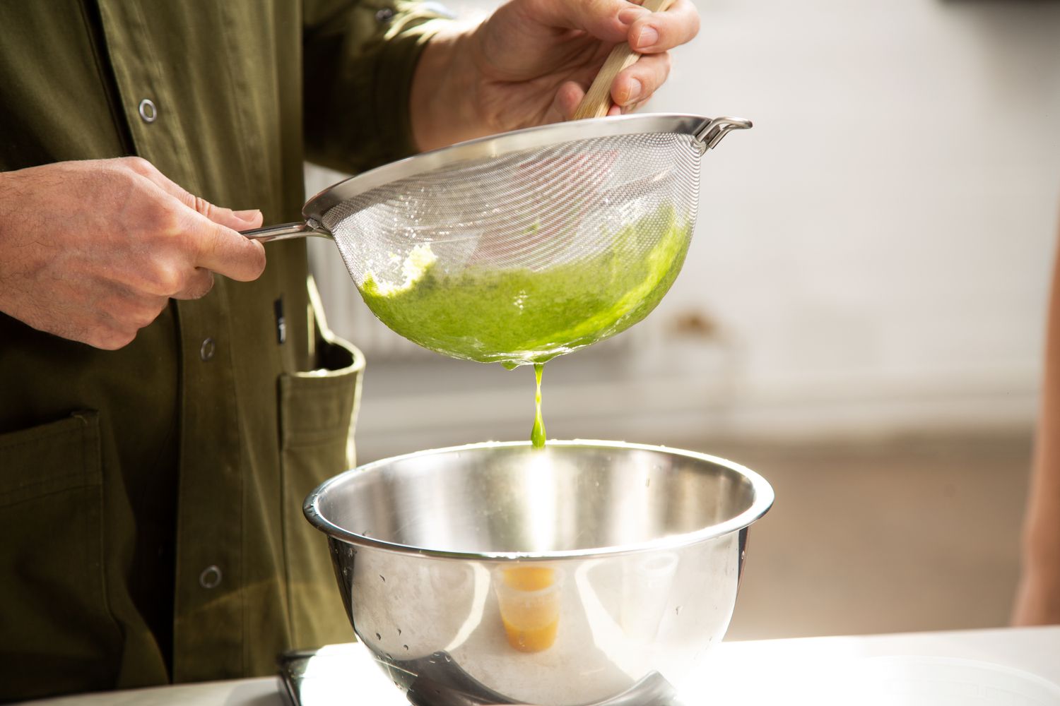 Smoothie pulp being strained through a fine mesh strainer.