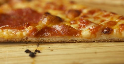 A close-up side view of bar pizza, showing the very thin crust.
