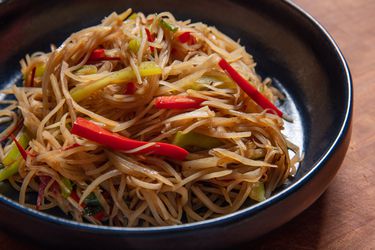 A plate of very thin strands of stir-fried potato and red and green pepper; the potato looks softened but not limp, and is a beige color that hints at the sauce it absorbed in the wok.