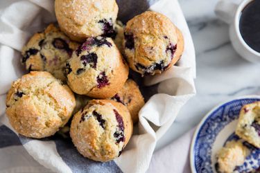 A cloth-lined basket of blueberry muffins