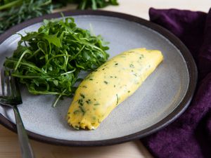 A classic French omelette on a place with arugula salad.