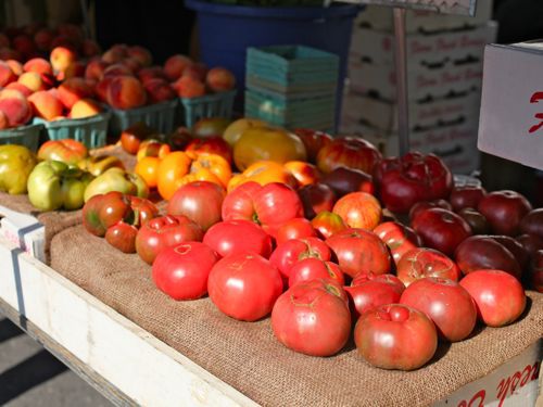 农贸市场的摊位上，一张铺着粗麻布的桌子上摆放着各种形状不规则的传家宝番茄，令人印象深刻。