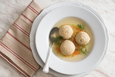 俯视图，一个浅白色碗里盛着的无酵丸子汤，点缀着莳萝枝。