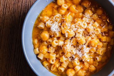 Pasta e ceci in a blue bowl with shredded Parmesan on top.