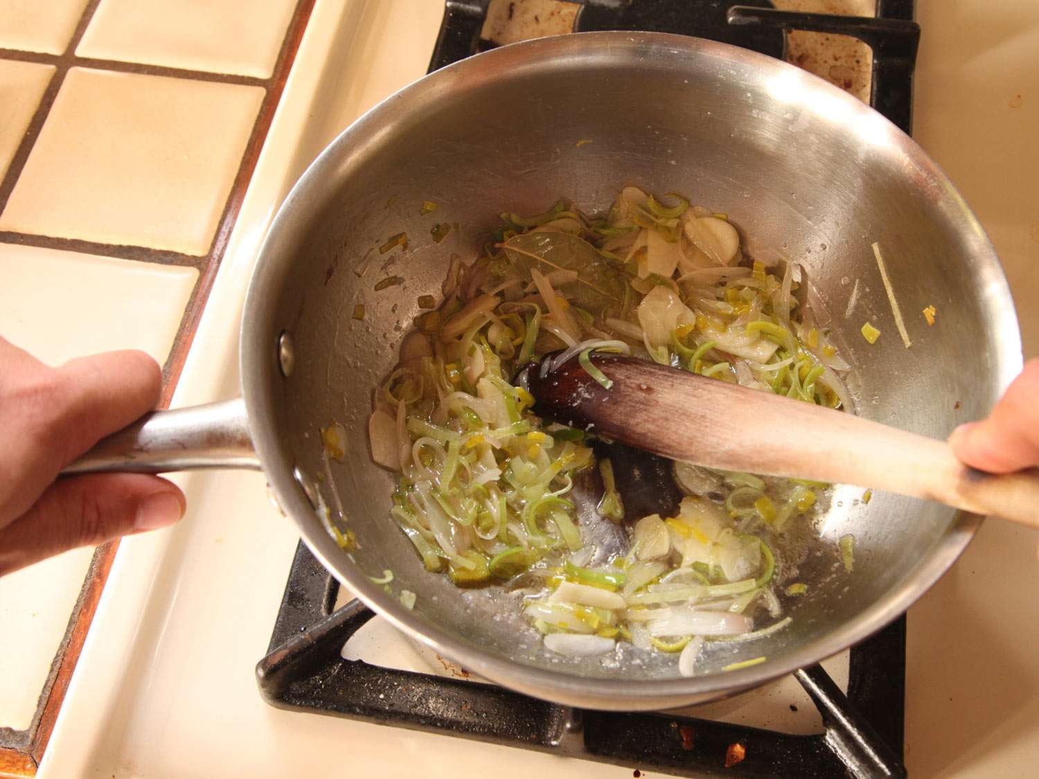 葱，韭菜和大蒜用黄油中火煮至软。切片的葱看起来软绵绵的，有点半透明。