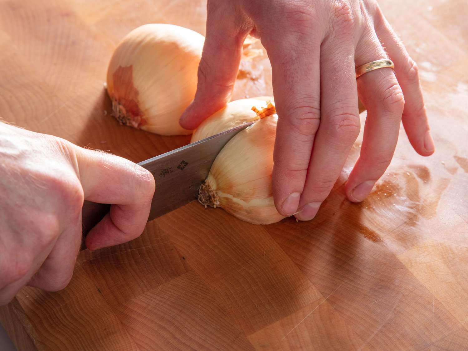 用厨师刀将洋葱从根部切成四等份。