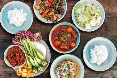 Overhead view of five Thai dishes, served with sticky rice.