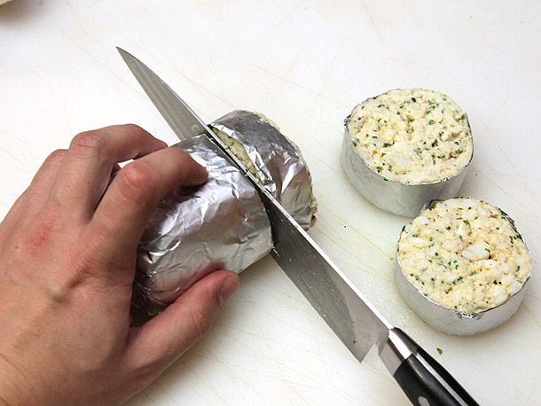 用厨师刀将用箔纸包裹的蟹肉饼切成4到6块，每块约1.5英寸厚
