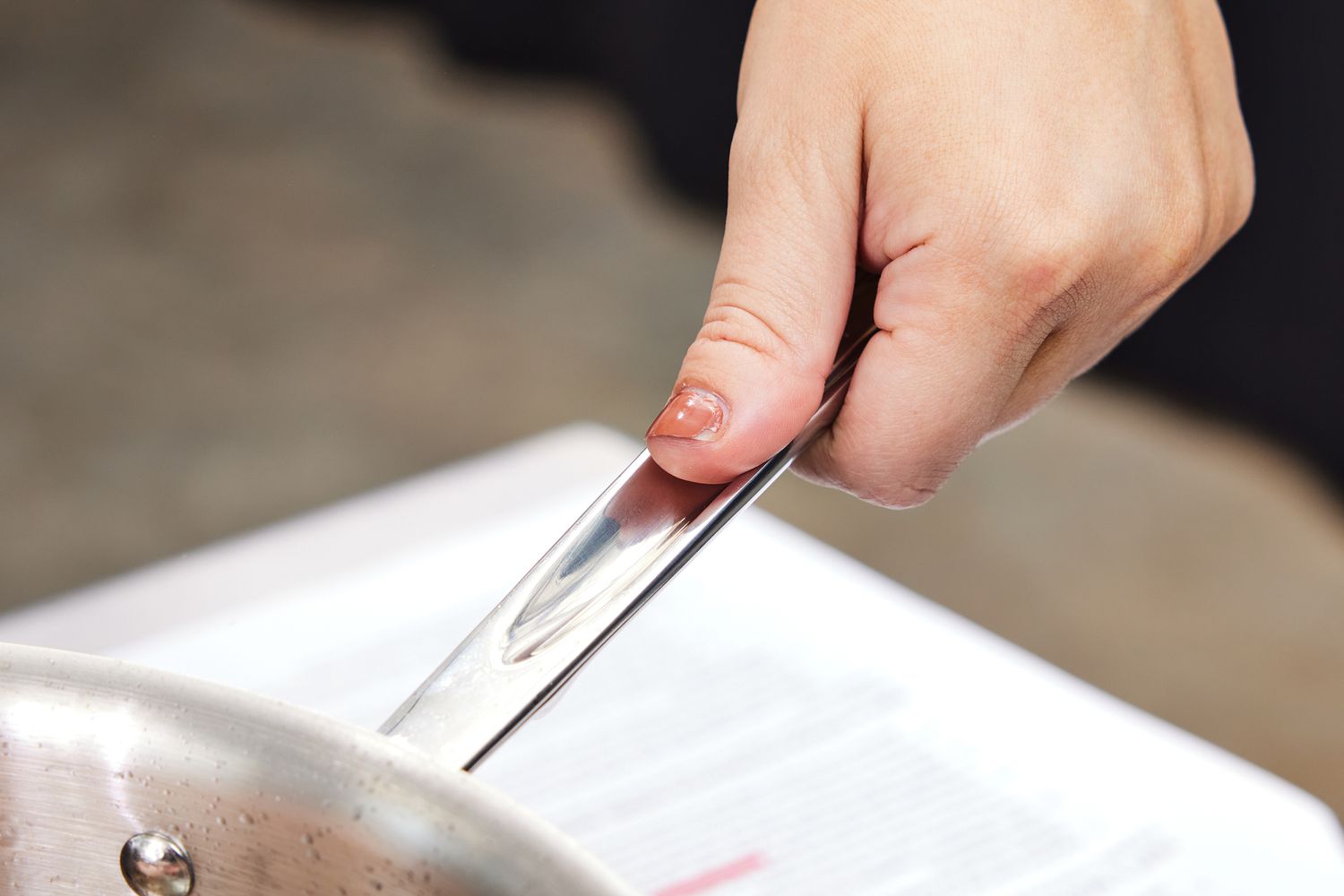 a closeup look of a person's thumb holding an all-clad's handle