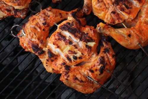 长着蝴蝶翅膀的康沃尔母鸡被烤串平摊在烤架上。