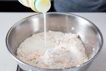 Cultured buttermilk is poured into a bowl to make the dough for cheddar bay biscuits.