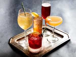 A tray with five glasses holding five different holiday cocktails