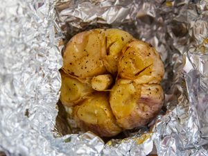 A bulb of roasted garlic wrapped in aluminum foil.