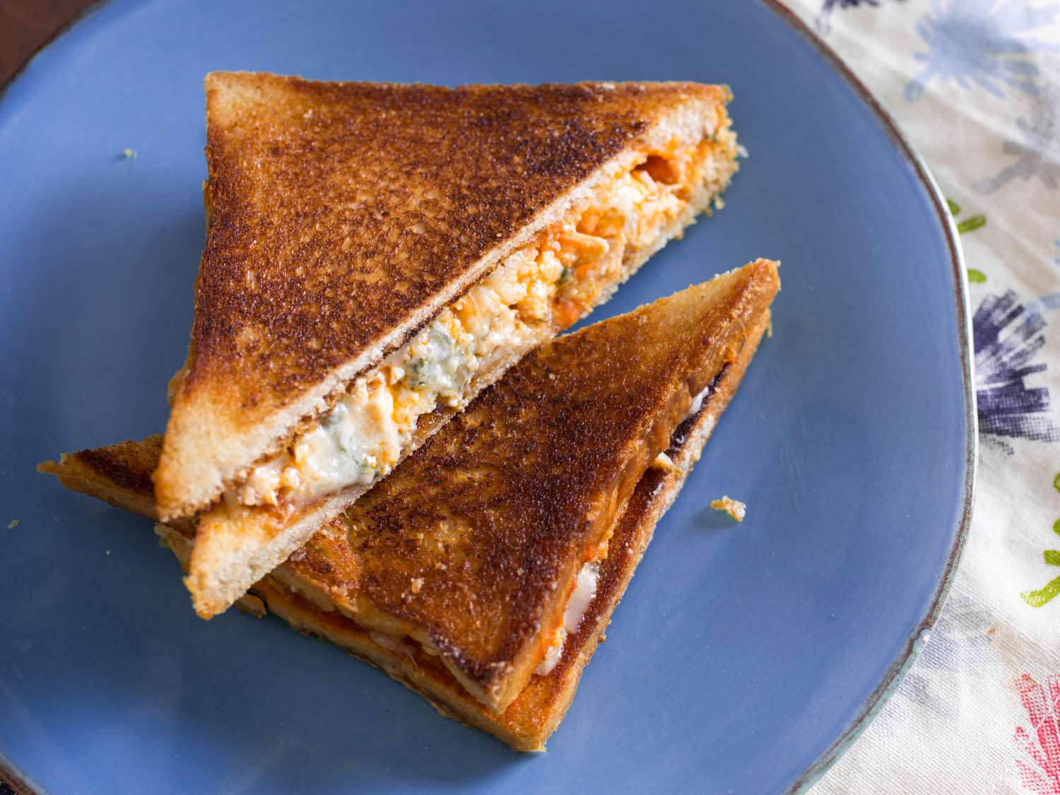 A Buffalo chicken grilled cheese sandwich halved and plated