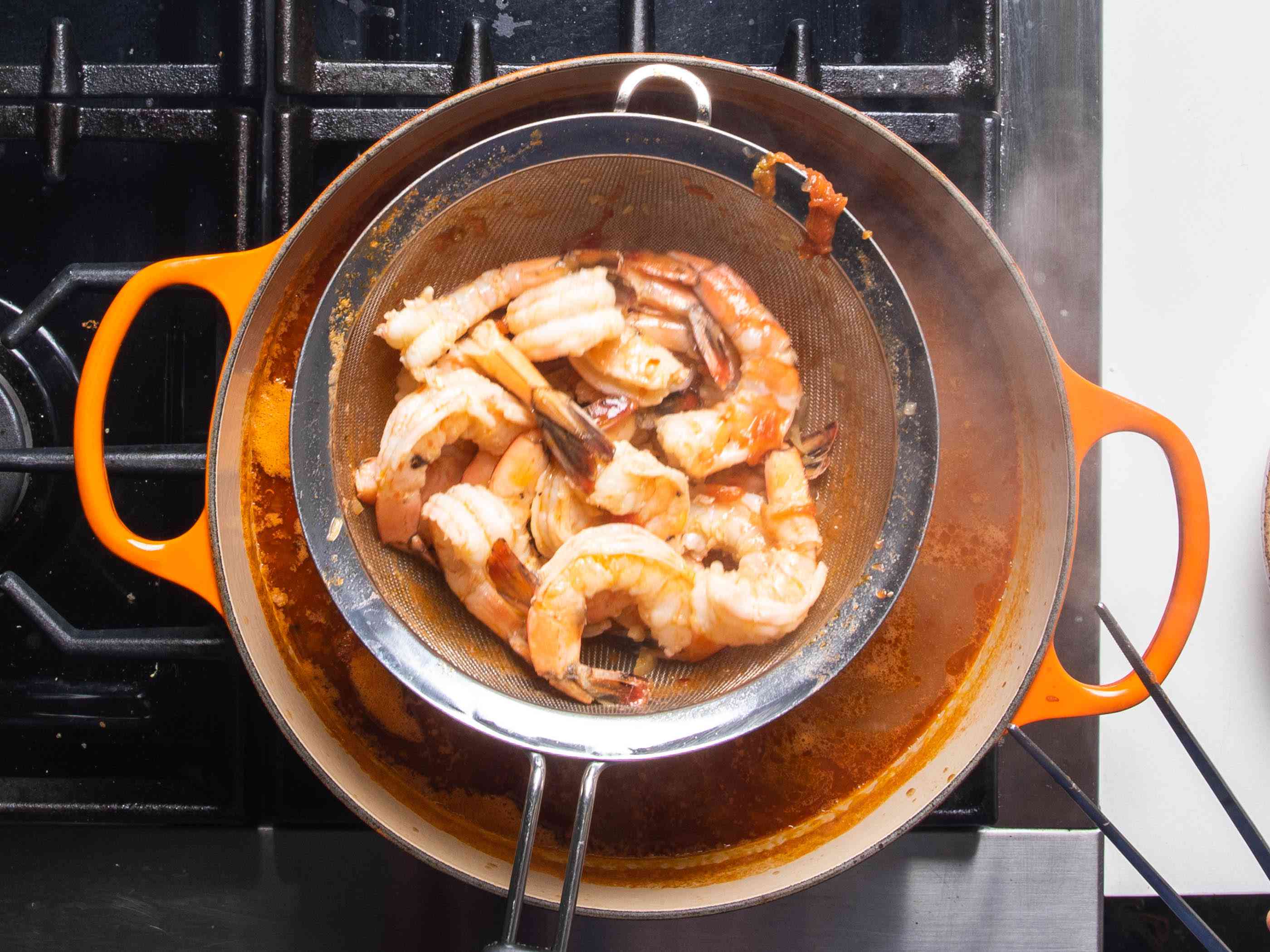 煮熟的虾被从肉汤中提出来，同时在过滤篮中。