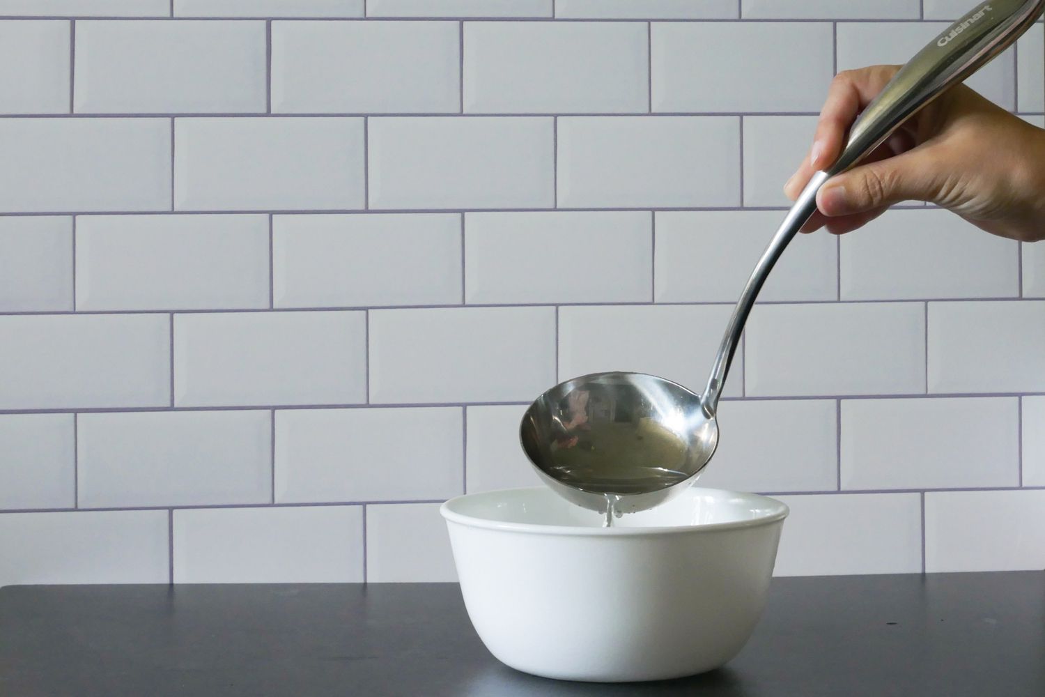 用煮菜勺将水倒进碗里，展示碗的形状。