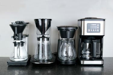 four inexpensive coffee makers on a gray background