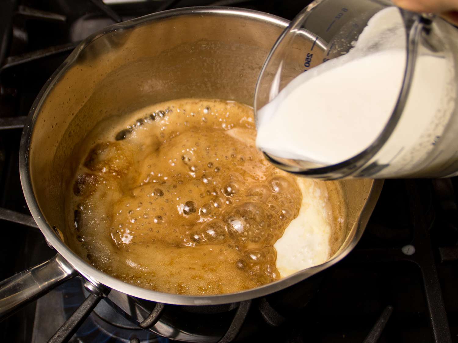 奶油被倒进焦糖里，放在炉子上的平底锅里。