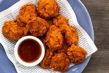 A pile of homemade chicken nuggets with a bowl of sweet 'n' sour sauce