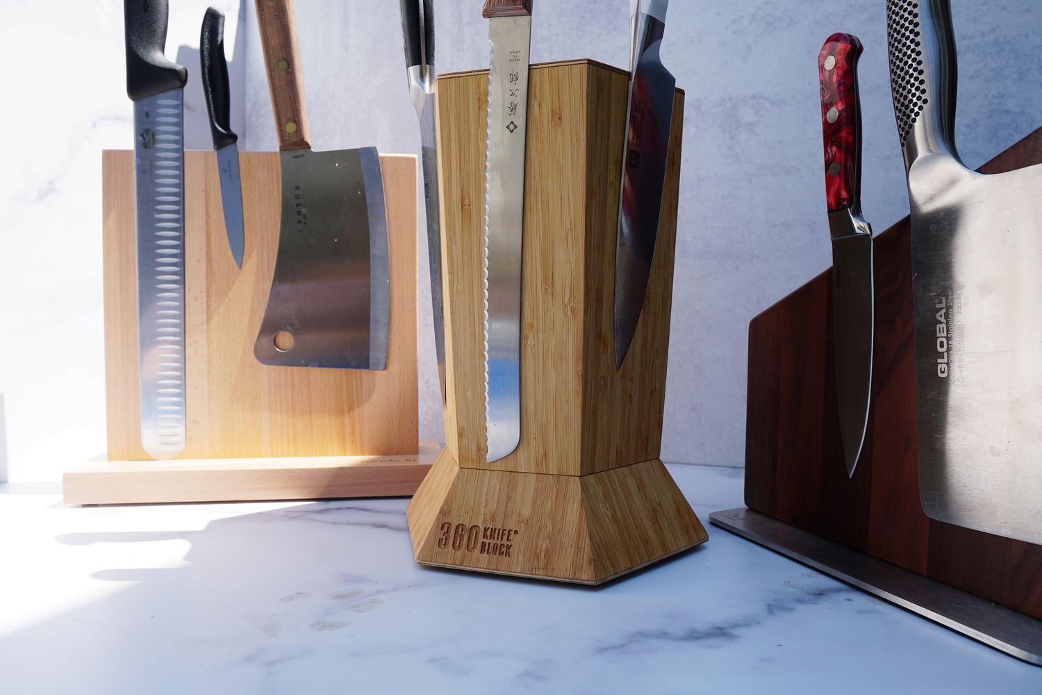 three knife blocks with knives on it on a marble surface