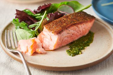 Crispy pan-seared salmon fillet served on a plate with greens