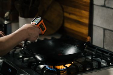 A thermometer pointed at a wok